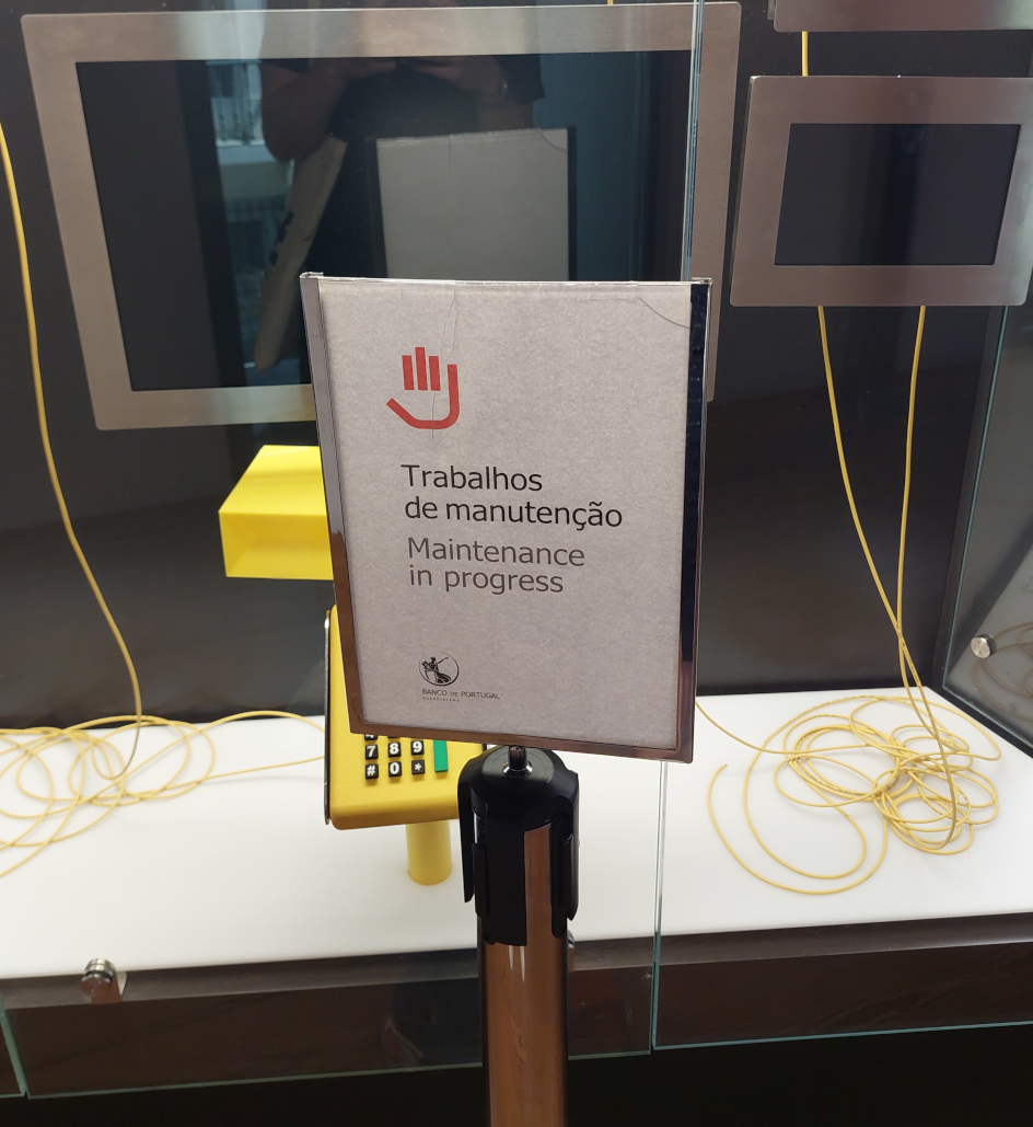Sign with 'Maintenance in Progress' in front of a non-functional display